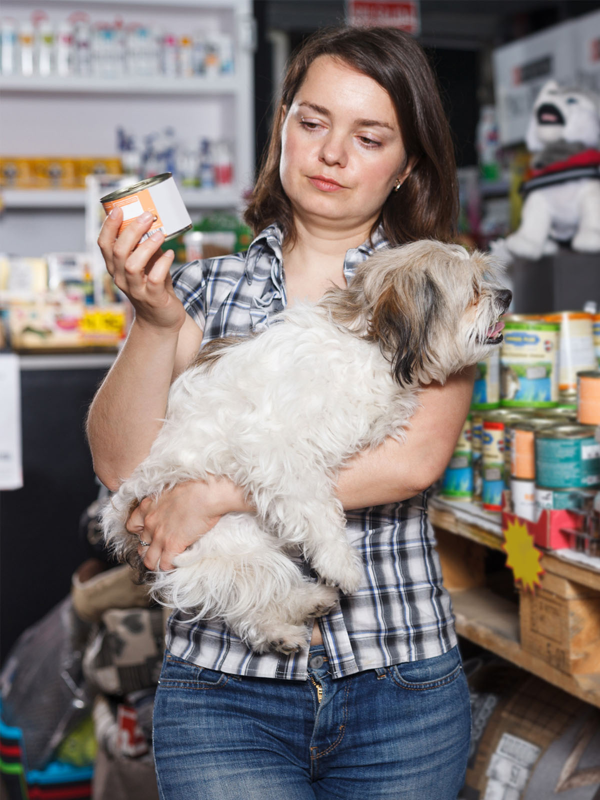 woman holding a dog and a pet food can while standing